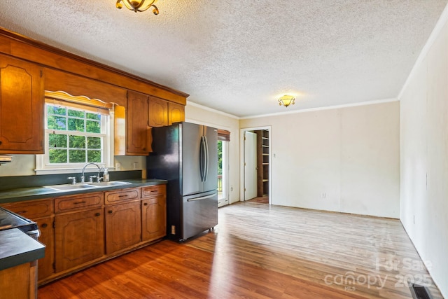 8706 Richardson King Rd, Waxhaw, NC 28173 - kitchen featuring freestanding refrigerator, crown molding, dark countertops, a textured ceiling, and brown cabinetry
