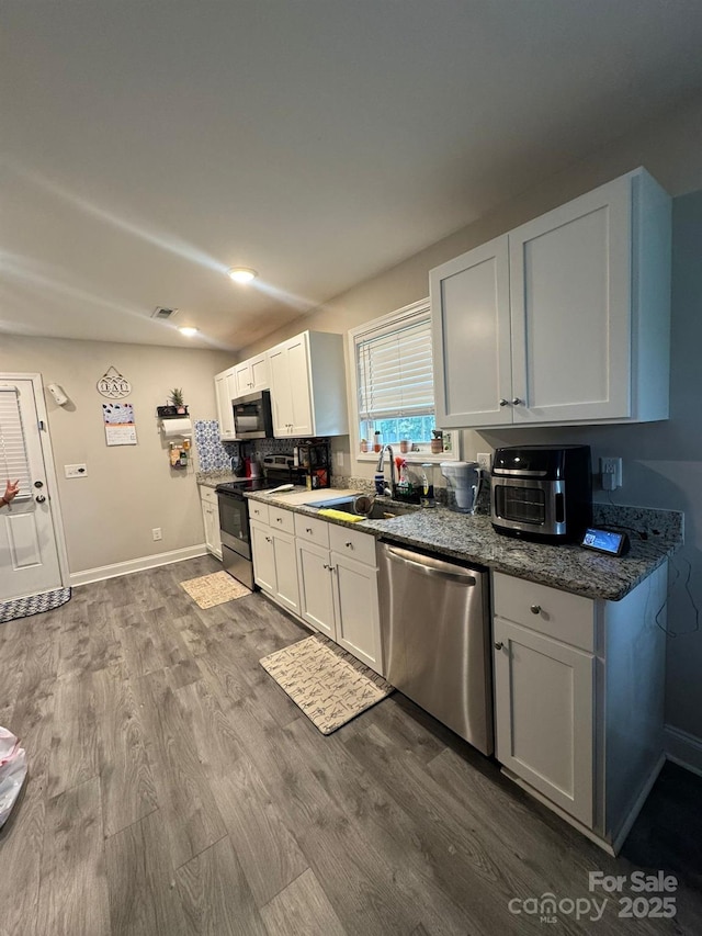 1017 W C St, Kannapolis, NC 28081 - kitchen featuring stainless steel appliances, white cabinetry, dark wood-style floors, dark stone counters, and tasteful backsplash