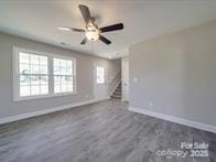 1017 W C St, Kannapolis, NC 28081 - unfurnished living room with stairway, ceiling fan, and dark wood-style flooring