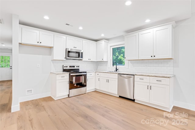 452 Duncan St, Spartanburg, SC 29306 - kitchen featuring appliances with stainless steel finishes, light wood finished floors, light stone countertops, white cabinets, and recessed lighting