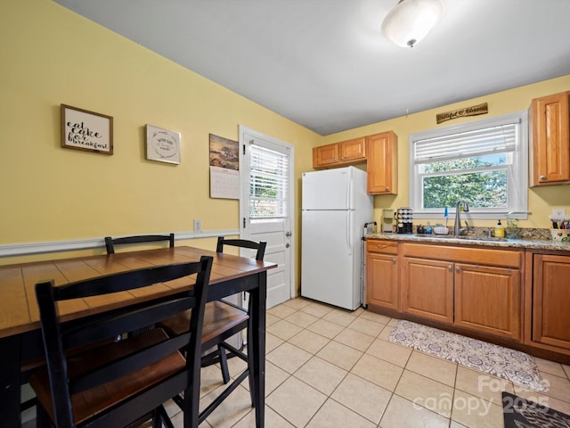 427 E 12th Ave, Gastonia, NC 28054 - kitchen with freestanding refrigerator, healthy amount of natural light, light tile patterned floors, and brown cabinetry