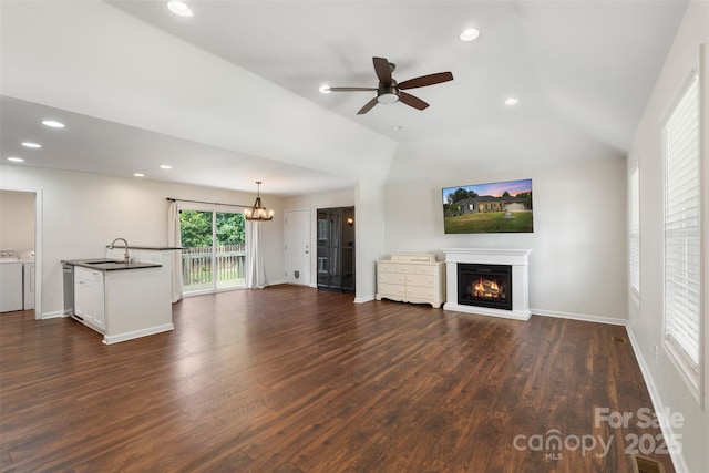 7627 Sarah Dr, Denver, NC 28037 - unfurnished living room featuring washer and dryer, a lit fireplace, vaulted ceiling, dark wood finished floors, and a ceiling fan