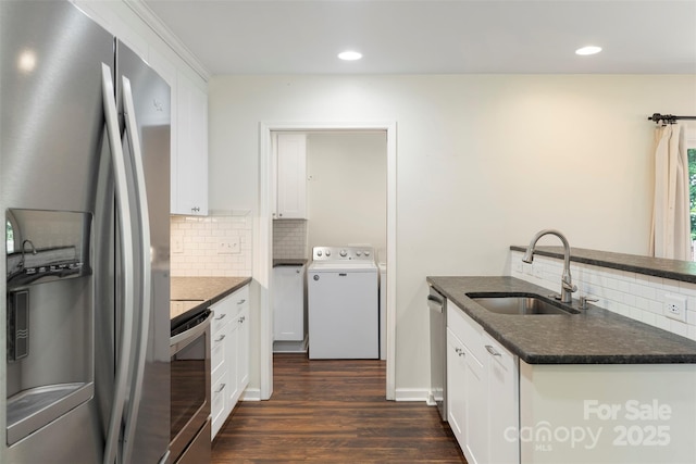 7627 Sarah Dr, Denver, NC 28037 - kitchen with appliances with stainless steel finishes, washer / clothes dryer, decorative backsplash, dark wood-style flooring, and white cabinetry
