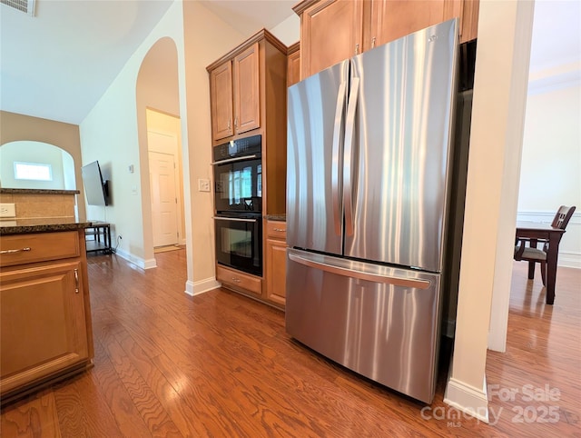 408 Presidio Dr, Rock Hill, SC 29732 - kitchen featuring freestanding refrigerator, dark wood-type flooring, dark stone countertops, arched walkways, and brown cabinetry