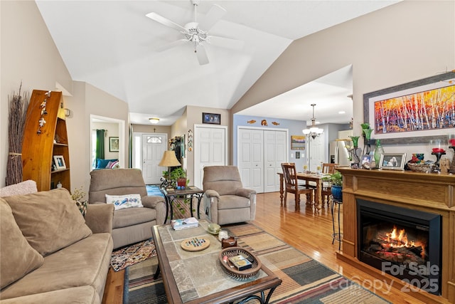 4 Orchard Pl, Weaverville, NC 28787 - living area featuring lofted ceiling, wood finished floors, a ceiling fan, a chandelier, and a glass covered fireplace