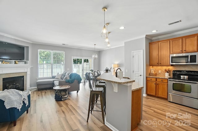 529 River Park Rd, Belmont, NC 28012 - kitchen featuring appliances with stainless steel finishes, crown molding, a kitchen bar, light stone counters, and open floor plan