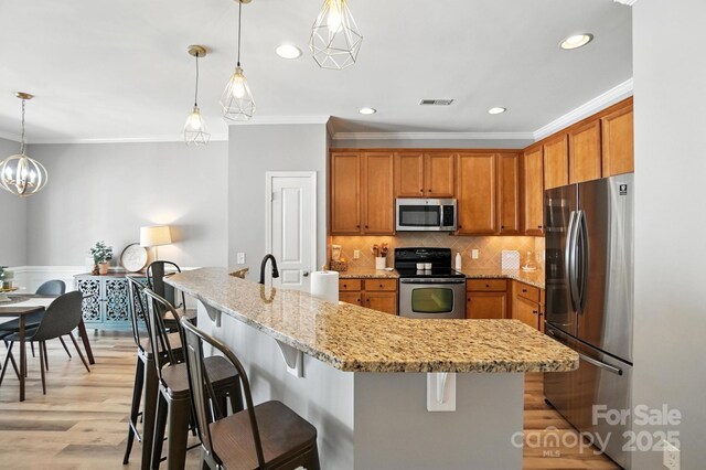 529 River Park Rd, Belmont, NC 28012 - kitchen with appliances with stainless steel finishes, crown molding, light wood-type flooring, brown cabinets, and a breakfast bar