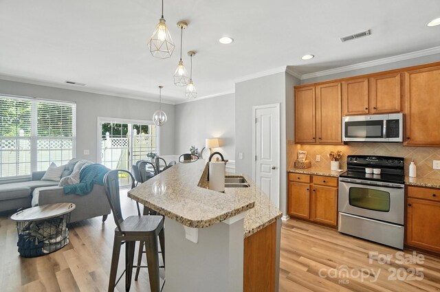 529 River Park Rd, Belmont, NC 28012 - kitchen featuring appliances with stainless steel finishes, light wood-type flooring, brown cabinets, a kitchen bar, and ornamental molding