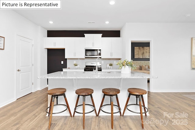 1357 Secrest Commons Dr, Monroe, NC 28112 - kitchen featuring appliances with stainless steel finishes, light wood-style floors, a kitchen breakfast bar, and recessed lighting