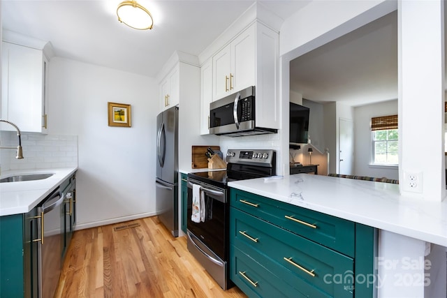 528 Wakefield Dr Unit A, Charlotte, NC 28209 - kitchen with stainless steel appliances, white cabinetry, decorative backsplash, and light wood-type flooring