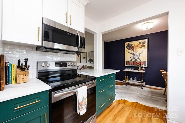 528 Wakefield Dr Unit A, Charlotte, NC 28209 - kitchen featuring stainless steel appliances, white cabinetry, tasteful backsplash, light wood-type flooring, and green cabinetry