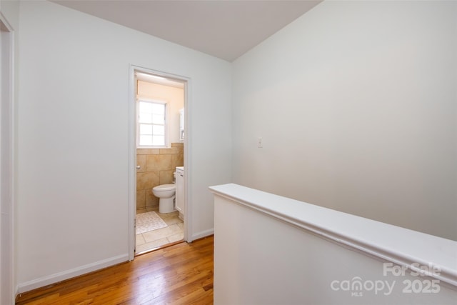 528 Wakefield Dr Unit A, Charlotte, NC 28209 - hallway with light wood-type flooring, tile walls, and an upstairs landing