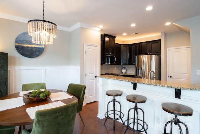 3537 Hornets Nest Way Unit 206, Charlotte, NC 28208 - kitchen with appliances with stainless steel finishes, a kitchen bar, light stone counters, a wainscoted wall, and crown molding