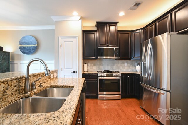 3537 Hornets Nest Way Unit 206, Charlotte, NC 28208 - kitchen with appliances with stainless steel finishes, ornamental molding, light stone counters, backsplash, and light wood-type flooring