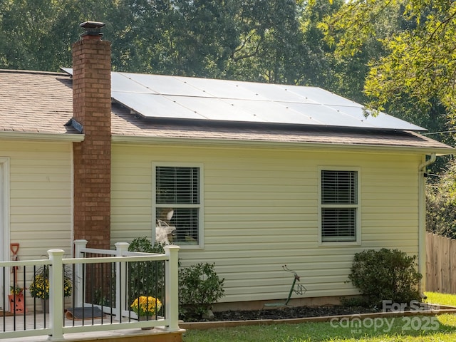 327 Downing St, Troutman, NC 28166 - view of side of home with a chimney, roof with shingles, and roof mounted solar panels