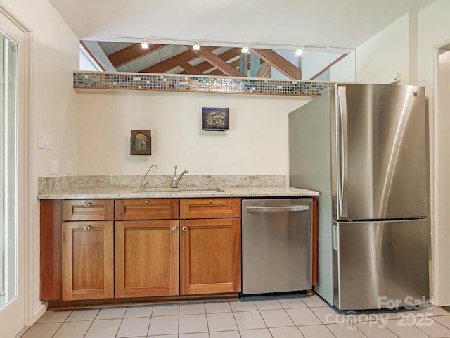 3310 Windbluff Dr, Charlotte, NC 28277 - kitchen featuring appliances with stainless steel finishes, brown cabinets, light stone counters, rail lighting, and light tile patterned floors