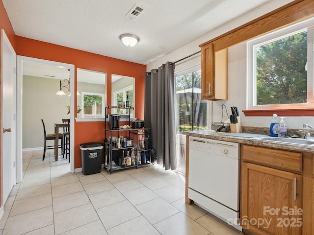 5701 Silver Eagle Dr, Charlotte, NC 28214 - kitchen featuring white dishwasher, light tile patterned flooring, brown cabinetry, and a textured ceiling