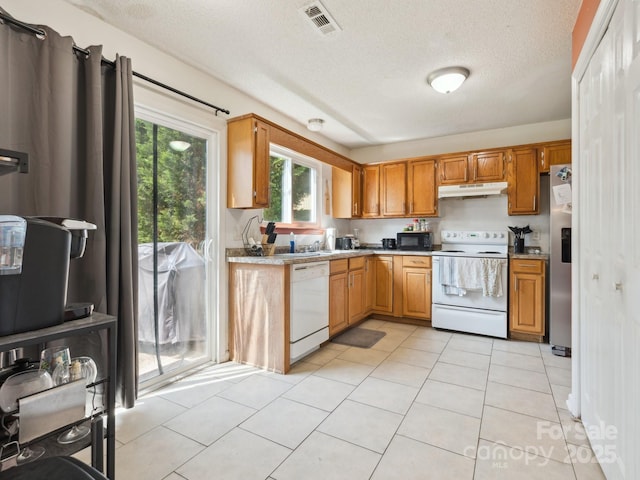 5701 Silver Eagle Dr, Charlotte, NC 28214 - kitchen with white appliances, under cabinet range hood, a textured ceiling, light tile patterned floors, and light countertops