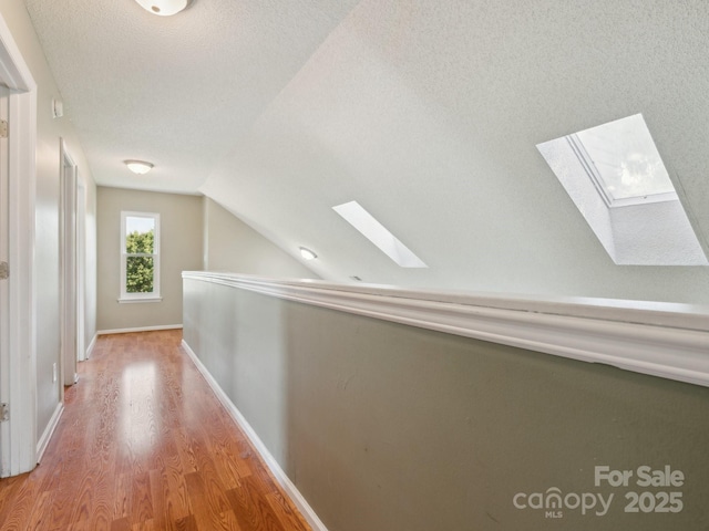 5701 Silver Eagle Dr, Charlotte, NC 28214 - hall with a skylight, wood finished floors, lofted ceiling, and a textured ceiling
