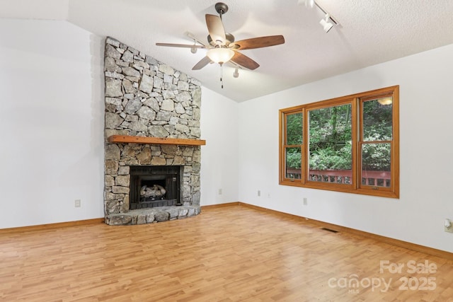 58 Oak Ter, Arden, NC 28704 - unfurnished living room featuring vaulted ceiling, wood finished floors, ceiling fan, track lighting, and a stone fireplace