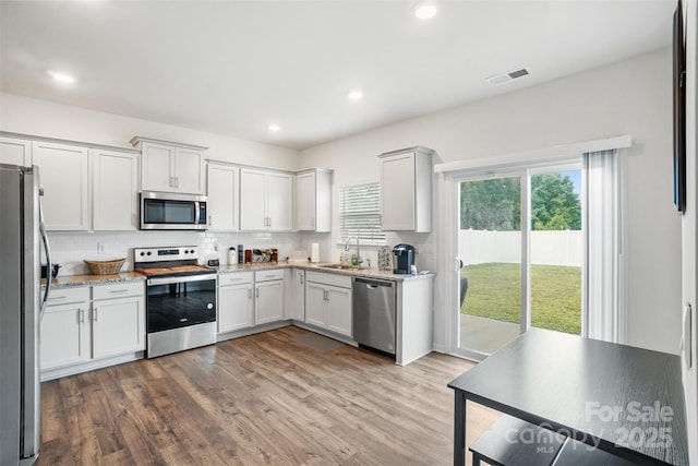 1343 Kent Downs Ave SW, Concord, NC 28027 - kitchen featuring appliances with stainless steel finishes, wood finished floors, tasteful backsplash, light stone countertops, and recessed lighting