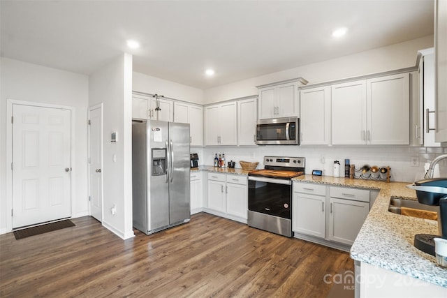 1343 Kent Downs Ave SW, Concord, NC 28027 - kitchen with stainless steel appliances, dark wood-style flooring, decorative backsplash, light stone counters, and recessed lighting
