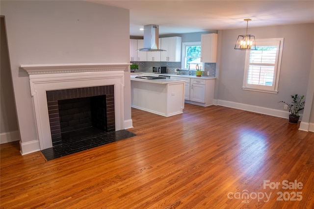 2115 Arnold Dr, Charlotte, NC 28205 - kitchen featuring island exhaust hood, light countertops, white cabinetry, backsplash, and light wood finished floors