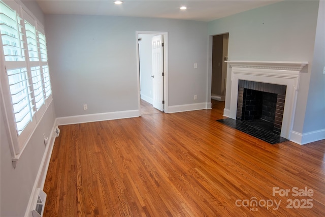 2115 Arnold Dr, Charlotte, NC 28205 - unfurnished living room featuring wood finished floors, a brick fireplace, and recessed lighting