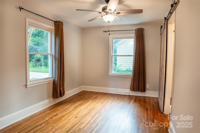 2115 Arnold Dr, Charlotte, NC 28205 - empty room featuring light wood-type flooring, a ceiling fan, and a barn door