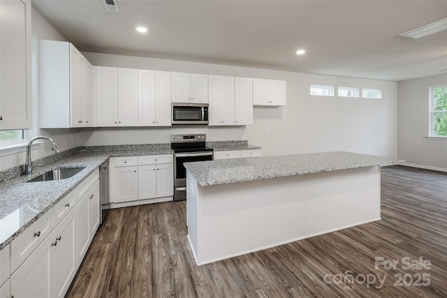 2591 Watson Dr, Lancaster, SC 29720 - kitchen featuring stainless steel appliances, dark wood finished floors, light stone counters, white cabinets, and a kitchen island