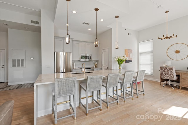 1315 E Blvd Unit 225, Charlotte, NC 28203 - kitchen with appliances with stainless steel finishes, light wood-style flooring, a kitchen bar, an office area, and a chandelier