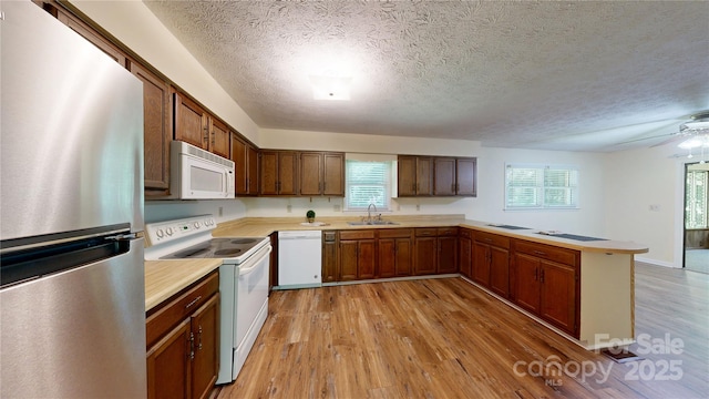 212 Fallen Timber Rd Unit 23, Hendersonville, NC 28791 - kitchen featuring white appliances, a peninsula, light wood-style floors, light countertops, and a textured ceiling