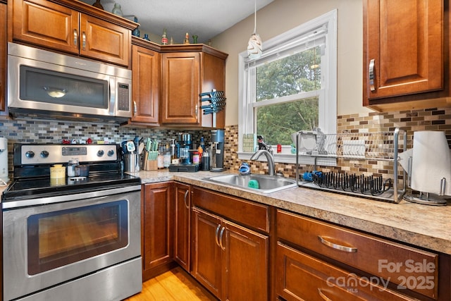 1467 Conway Dr, Granite Falls, NC 28630 - kitchen with appliances with stainless steel finishes, light countertops, brown cabinetry, tasteful backsplash, and hanging light fixtures