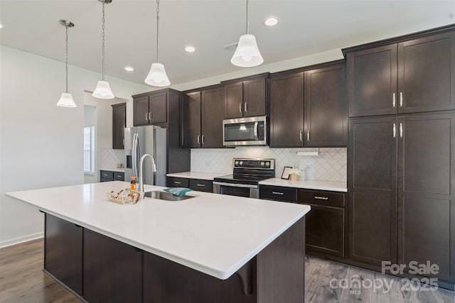 117 Carmine Ct, Troutman, NC 28166 - kitchen with stainless steel appliances, wood finished floors, an island with sink, backsplash, and light countertops