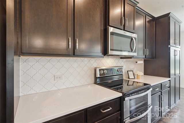 117 Carmine Ct, Troutman, NC 28166 - kitchen featuring appliances with stainless steel finishes, dark brown cabinets, decorative backsplash, light countertops, and wood finished floors