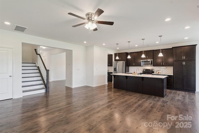 117 Carmine Ct, Troutman, NC 28166 - kitchen featuring appliances with stainless steel finishes, light countertops, a breakfast bar area, dark brown cabinets, and recessed lighting