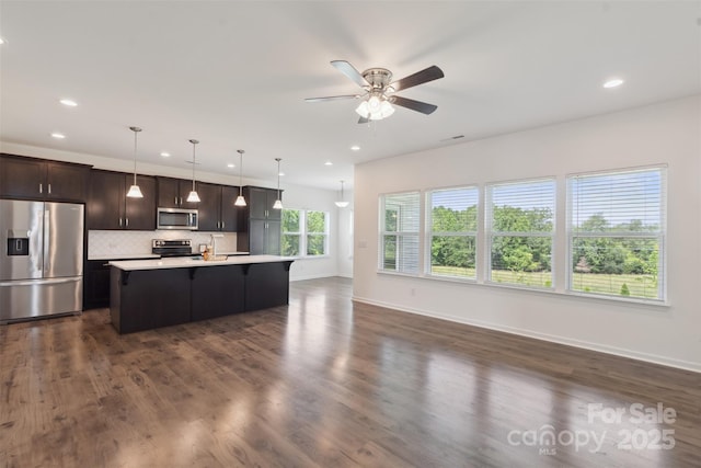117 Carmine Ct, Troutman, NC 28166 - kitchen featuring appliances with stainless steel finishes, light countertops, tasteful backsplash, a center island with sink, and dark brown cabinets