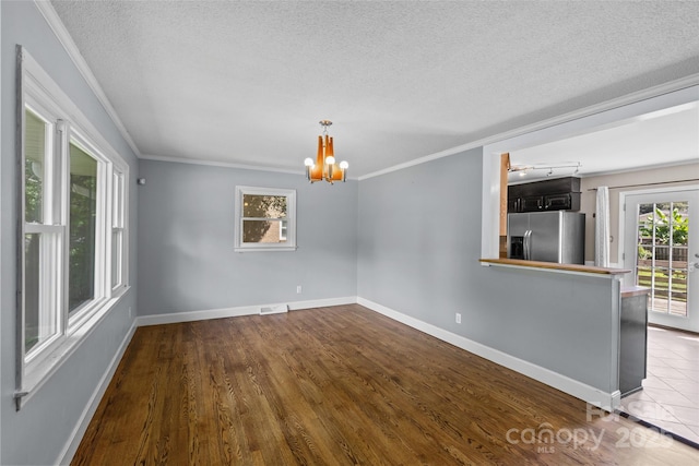 2000 Townsend Ave, Charlotte, NC 28205 - unfurnished living room with a chandelier, a textured ceiling, ornamental molding, and dark wood finished floors