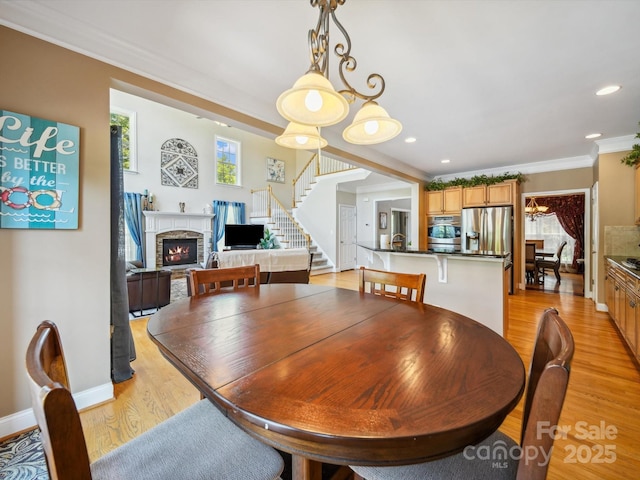 6523 Alba Rose Ln, Huntersville, NC 28078 - dining space featuring a fireplace, stairway, ornamental molding, light wood-style floors, and recessed lighting