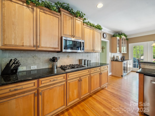 6523 Alba Rose Ln, Huntersville, NC 28078 - kitchen with stainless steel appliances, light wood-style flooring, dark stone counters, brown cabinets, and crown molding