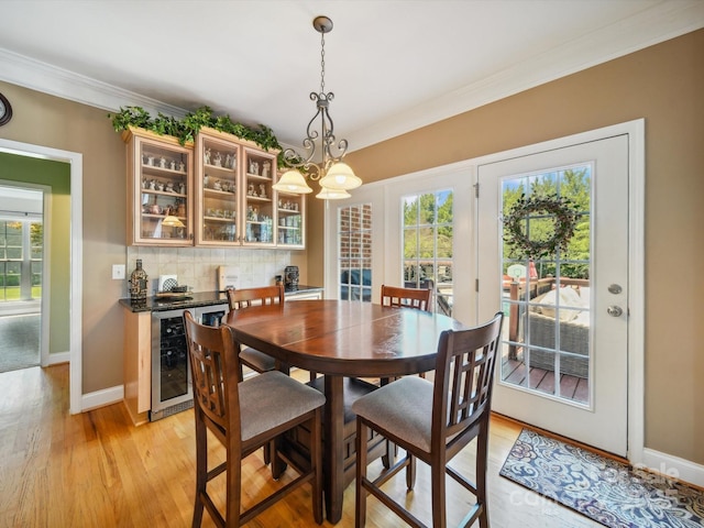 6523 Alba Rose Ln, Huntersville, NC 28078 - dining room featuring beverage cooler, ornamental molding, light wood-style flooring, and plenty of natural light