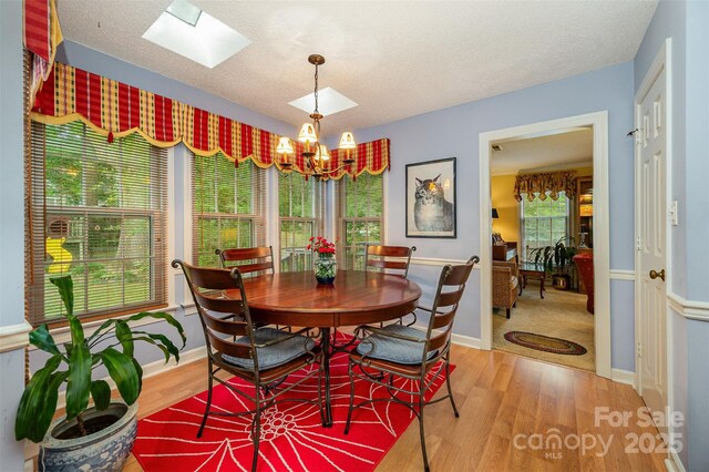 13416 Kintyre Ct, Matthews, NC 28105 - dining space featuring a skylight, wood finished floors, a chandelier, and a textured ceiling
