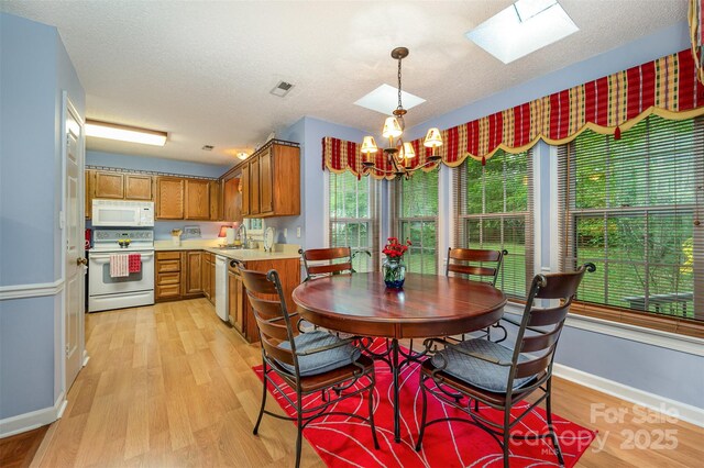 13416 Kintyre Ct, Matthews, NC 28105 - dining space with a skylight, light wood-style floors, a chandelier, and a textured ceiling