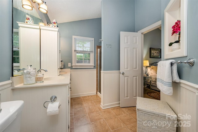 13416 Kintyre Ct, Matthews, NC 28105 - bathroom featuring a wainscoted wall, lofted ceiling, a shower stall, tile patterned flooring, and vanity