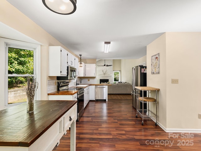 345 Bob Barnwell Rd, Fletcher, NC 28732 - kitchen featuring appliances with stainless steel finishes, dark wood-type flooring, tasteful backsplash, a fireplace, and white cabinetry