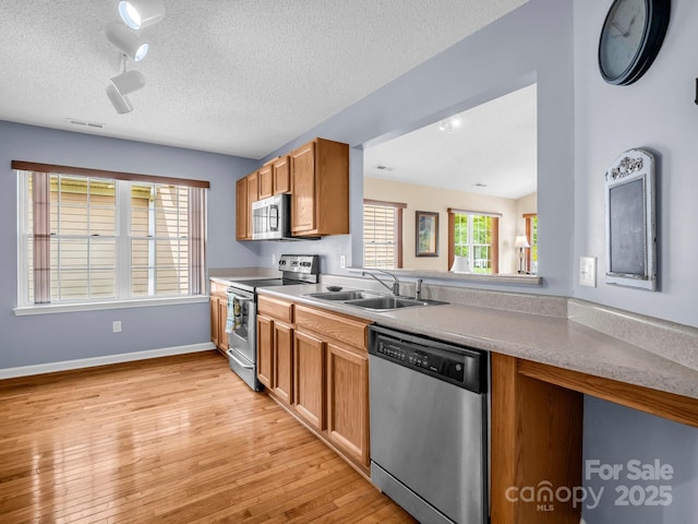 114 Fairway View Dr, Etowah, NC 28729 - kitchen featuring appliances with stainless steel finishes, light wood-style flooring, light countertops, a textured ceiling, and brown cabinetry