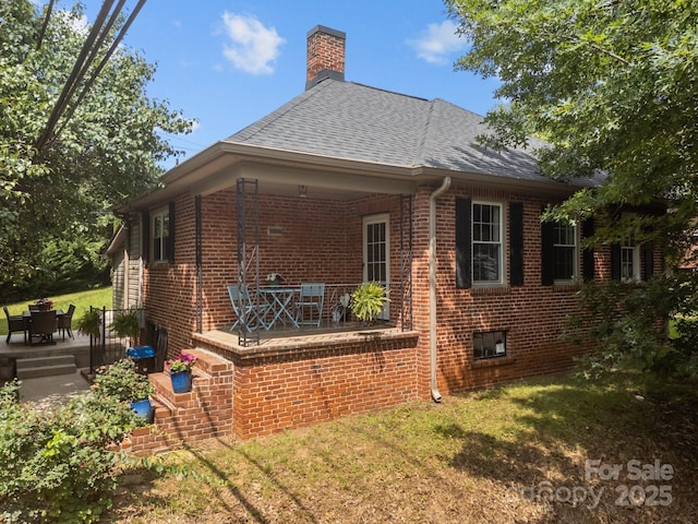 2 Enka Orchard St Unit 21A, Candler, NC 28715 - rear view of house featuring brick siding, roof with shingles, a yard, and a chimney