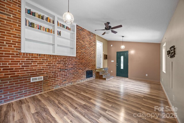 2 Enka Orchard St Unit 21A, Candler, NC 28715 - unfurnished living room with ceiling fan, wood finished floors, brick wall, a textured ceiling, and vaulted ceiling