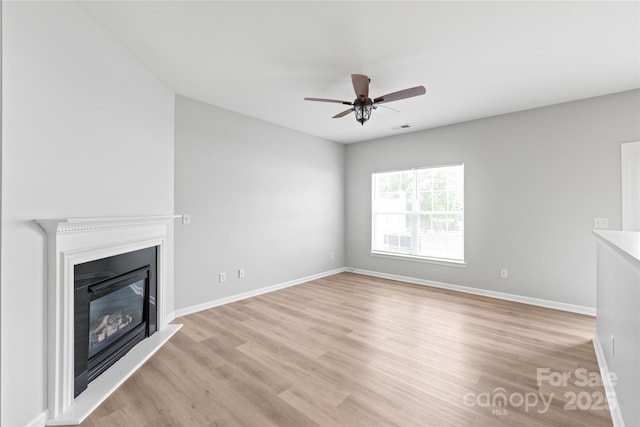 12452 Stratfield Place Cir, Pineville, NC 28134 - unfurnished living room with light wood-type flooring, ceiling fan, and a glass covered fireplace