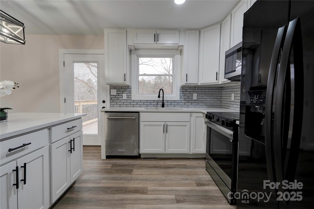 238 Lincoln Dr, Forest City, NC 28043 - kitchen featuring black appliances, white cabinets, decorative backsplash, light countertops, and light wood-style floors